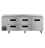A three-section stainless steel worktop refrigerator with six black-handled compartments, four center drawers, and two doors on each side sits on caster wheels. The unit features a vent on the bottom left, a flat top, and a raised rear edge.
