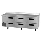 A large Hoshizaki stainless steel worktop refrigerator with six pull-out drawers, black handles, a smooth countertop, raised back edge, and caster wheels. A small vent panel is located on the left side of the unit’s front.