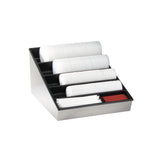 A sleek black and metallic lid organizer holds stacked white plastic lids in four angled rows, alongside red and white stirrers in two front compartments. This stylish countertop condiment organizer is perfect for dispensing coffee accessories. The background is plain white.