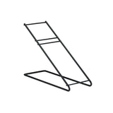 A black metal Angled Stand with a minimalist, wire black frame. It features two parallel rods forming a sloped surface, supported by a rectangular base with Dispense-Rite style horizontal bars connecting the sloped rods. The background is white.