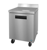 A Hoshizaki stainless steel worktop refrigerator or freezer with a single door, flat countertop, small backsplash, and black recessed handle. It stands on four caster wheels for mobility and features a small round blue logo on the bottom right corner.