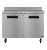 This ENERGY STAR worktop refrigerator features a smooth, metallic stainless steel finish, two doors with black recessed handles, four caster wheels, a raised rear edge on top, and a small blue logo in the lower right corner.