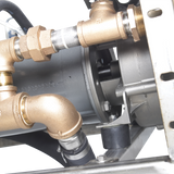 Close-up of industrial plumbing connections with brass fittings attached to a cylindrical gray metallic component, likely a Hobart WastePro self-contained pulper or motorized drain valve, mounted on a metal bracket against a black background.