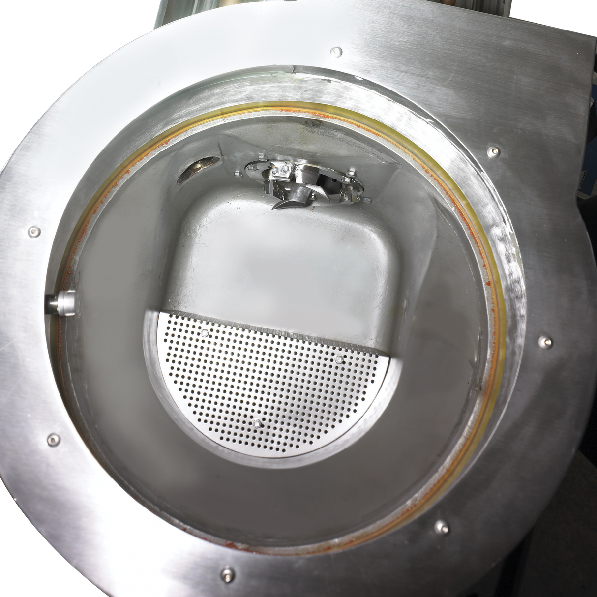 A close-up view of a shiny metal industrial machine, possibly a WastePro self-contained pulper, showing a circular opening with a perforated plate and smooth inner chamber. The well-maintained machine is likely used for processing or separating materials.