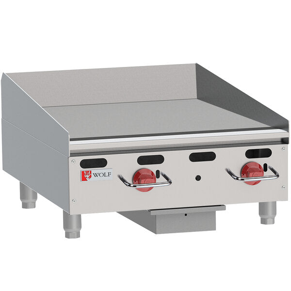 A heavy duty commercial griddle with stainless steel countertop design, two red control knobs, raised sides and backsplash, and sturdy short legs. The Wolf brand logo is displayed on the front left side of this reliable appliance.