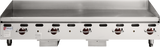 A large, heavy duty griddle, the Wolf AGM60_NAT features six red control knobs on its front panel. This commercial gas griddle boasts a clean, reflective flat surface and backsplash, with the Wolf logo displayed on the left side.