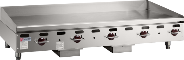 A large commercial gas griddle, the Wolf AGM60_NAT features four red control knobs, vent holes, a backsplash, and a flat stainless steel surface. This heavy duty griddle stands on short legs with the Wolf brand label visible on the left side.