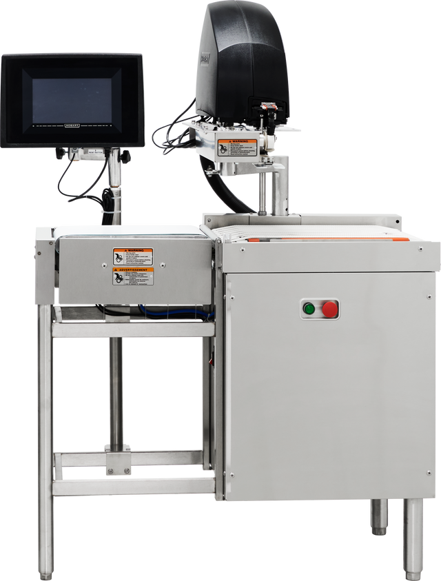 A Hobart stainless steel industrial checkweigher with a conveyor belt, digital display screen on the left, and black equipment housing on top. Warning labels and control buttons are visible. The sturdy stainless steel construction stands on metal legs.