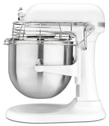A white KitchenAid Commercial Stand Mixer with an 8 quart stainless steel mixing bowl and wire safety guard is shown in profile. The base and body are white, and the bowl sits on a lifting arm beneath the mixing attachment above.