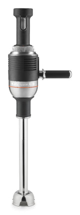A black and silver KitchenAid immersion blender stands upright, featuring a long stainless steel blending shaft and a black handle protruding from the side. The top section has a textured grip and visible control dial, highlighting its commercial immersion blender design.