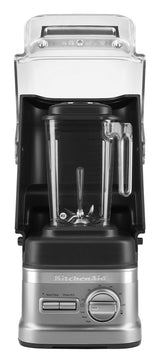 A silver and black KitchenAid Commercial Blender with a 60 oz. capacity features a clear plastic pitcher and handle, front-facing. It includes a control dial, several buttons, and an enclosure blender sound shield raised above the pitcher. Brand name visible on base.