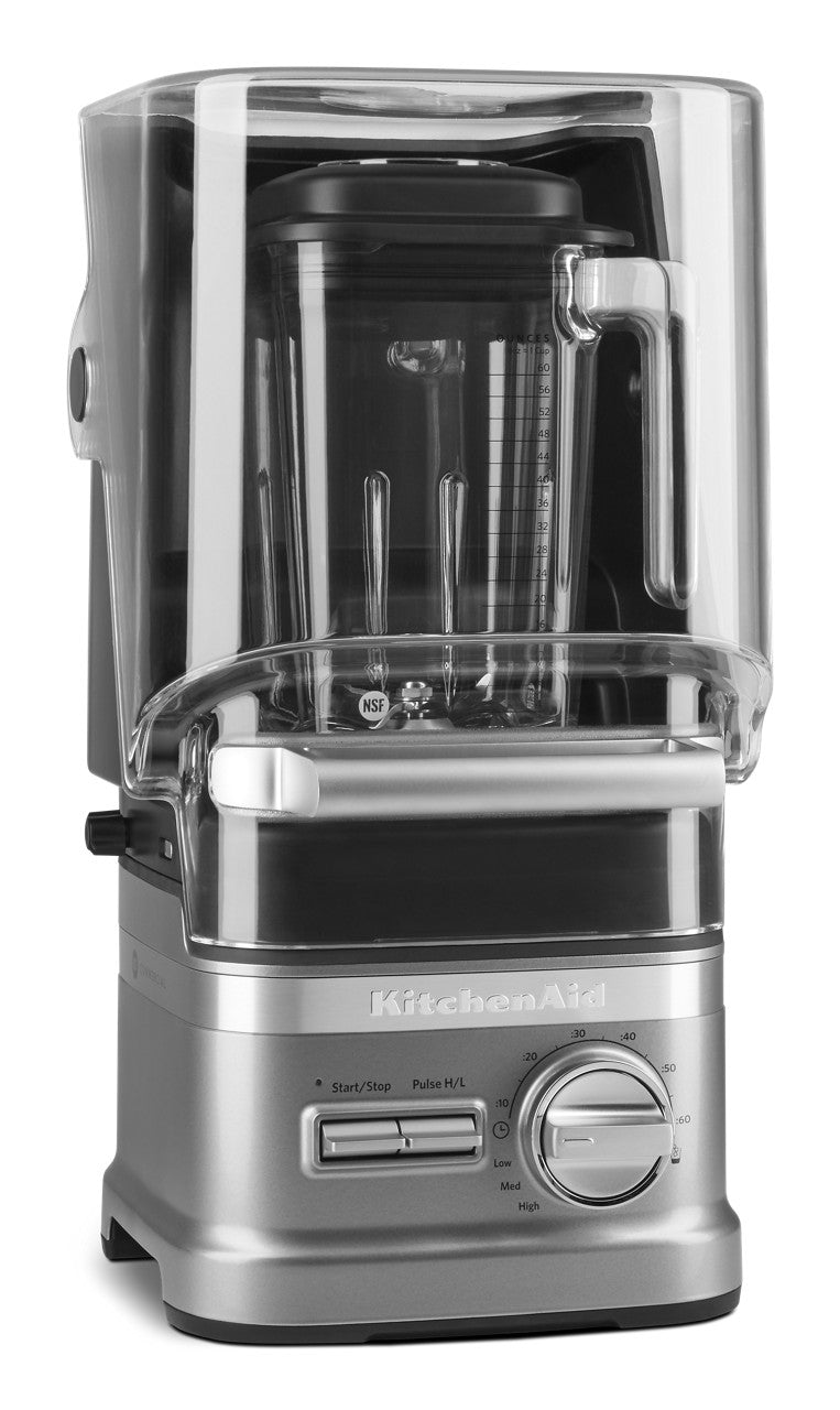 A silver KitchenAid Commercial Blender with a clear, fitted sound enclosure features a large dial, digital controls, and a visible 60 oz. capacity jar. This Enclosure Blender boasts a modern, professional design for any countertop.