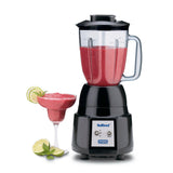 A black NuBlend Blender with a durable copolyester container is filled with a red smoothie, set beside a margarita glass of the same drink, garnished with lime and mint. Extra lime wedges and a mint sprig rest nearby on a white background.