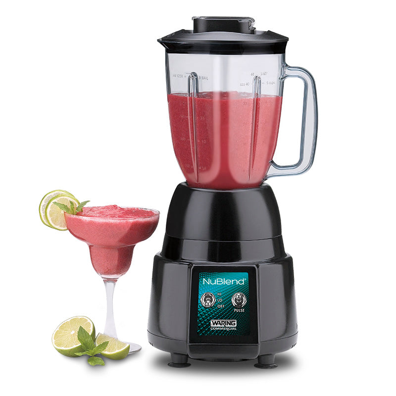 A black NuBlend commercial blender with a polycarbonate container is filled with a red smoothie on a white surface. Next to it, a cocktail glass holds the same smoothie, garnished with lime slices and extra lime wedges nearby.