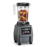 A 1 Gallon Blender with a clear plastic pitcher filled with colorful fruits and vegetables. The heavy-duty black and gray base features labeled buttons, a digital screen, and the CB15 PRE PROGRAM brand on the control panel.