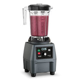 A commercial 1 gallon blender with a clear plastic container filled with thick, pink smoothie. The container has measurement markings and a black lid. The gray base features control buttons, rotary dial, indicator lights, and the CB15 brand label.