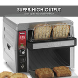 A Commercial Conveyor Toaster with stainless steel construction toasts four slices of multigrain bread. Two slices are in the wire rack, while two toasted slices and a bagel rest on the counter. The control panel reads “SUPER-HIGH OUTPUT.”.