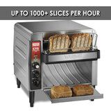 A stainless steel toaster with metal housing toasts four slices of bread. Two slices are in the rack, and two toasted slices rest on the pull-out tray. A sign above reads "UP TO 1000+ SLICES PER HOUR.” Control knobs and switches are on the left panel.