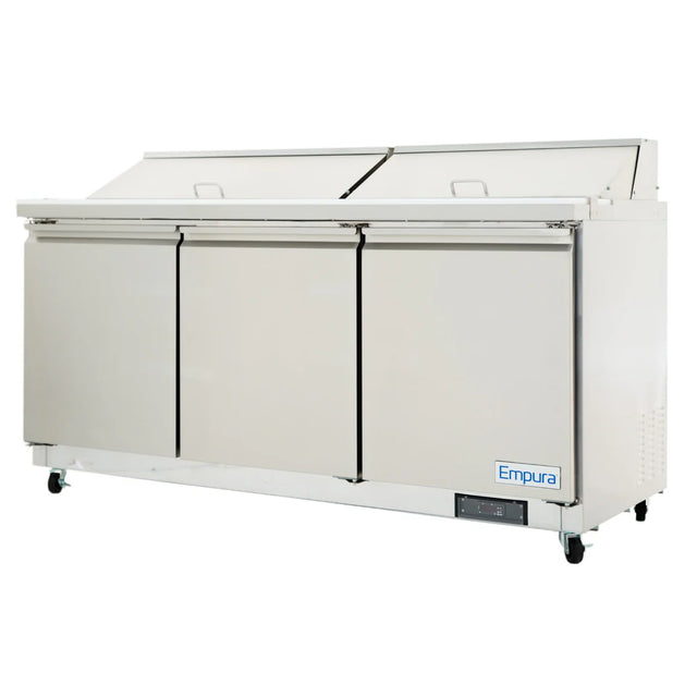 A large stainless steel commercial refrigeration unit with three front doors, two horizontal lids on top, and the Empura brand displayed on the lower right corner. This refrigerated sandwich prep table is set on caster wheels for easy mobility.