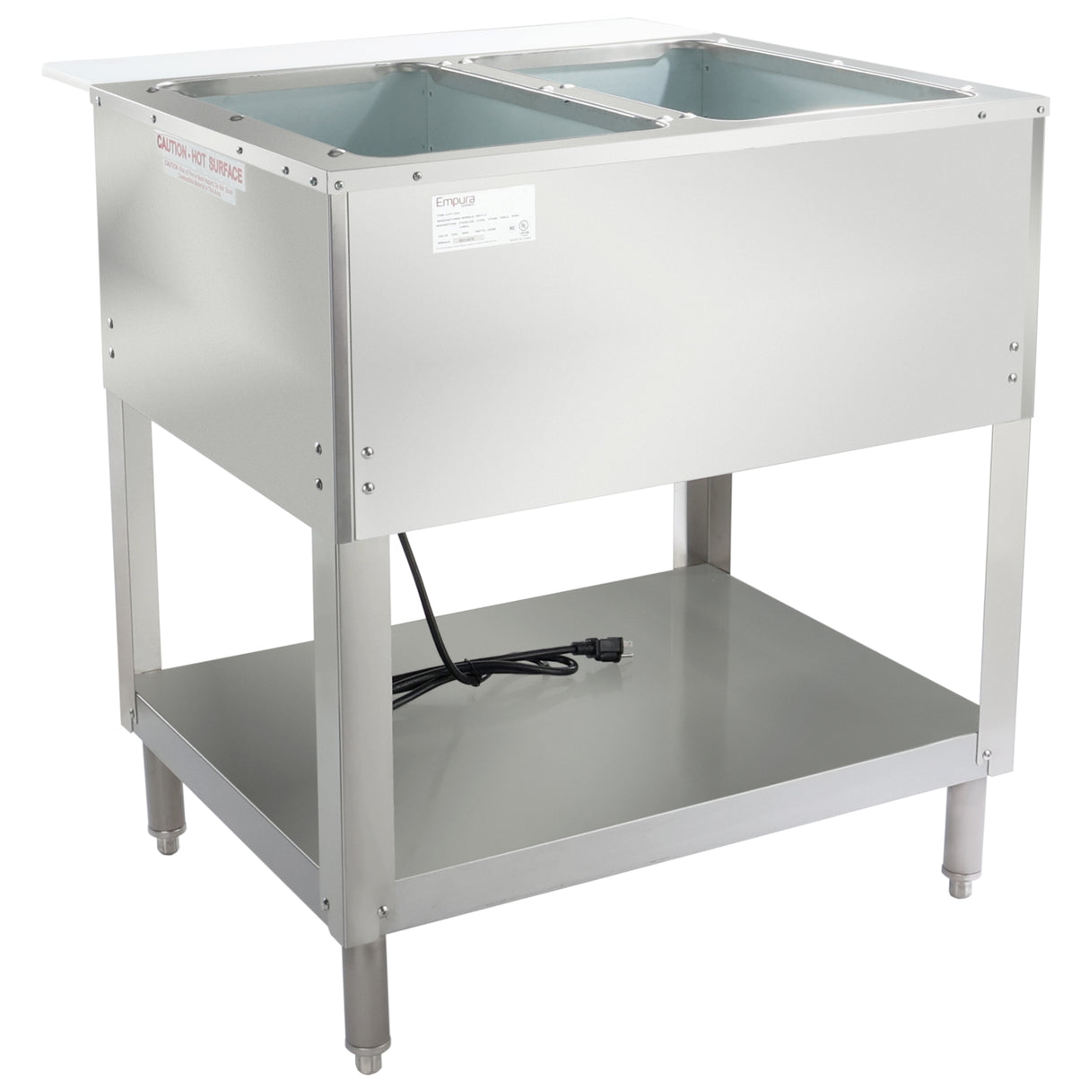 A stainless steel electric steam table with two open rectangular wells on top, a shelf below, four legs, and a visible power cord. The unit has a smooth surface and a “Caution: Hot Surface” label on the front left corner.