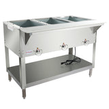 A commercial stainless steel 3-well steam table features control knobs on the front, an open lower shelf, four sturdy legs, and a power cord resting on the shelf. The top includes three rectangular wells for holding food pans.