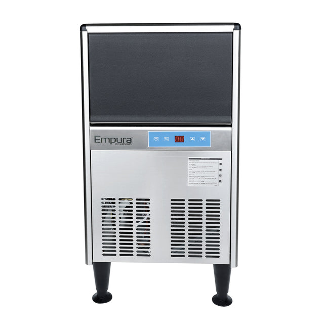 A stainless steel commercial ice machine by Empura stands on four black legs. It features a black top section, blue control panel with buttons and display, “Empura” label, air vents at the bottom, and a small instruction sticker.