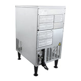 A commercial ice machine with a rectangular, industrial design stands on four black legs. The back panel features warning labels, ventilation grilles, a yellow caution symbol, and a black power cord. This stainless steel ice maker is built for durability and performance.