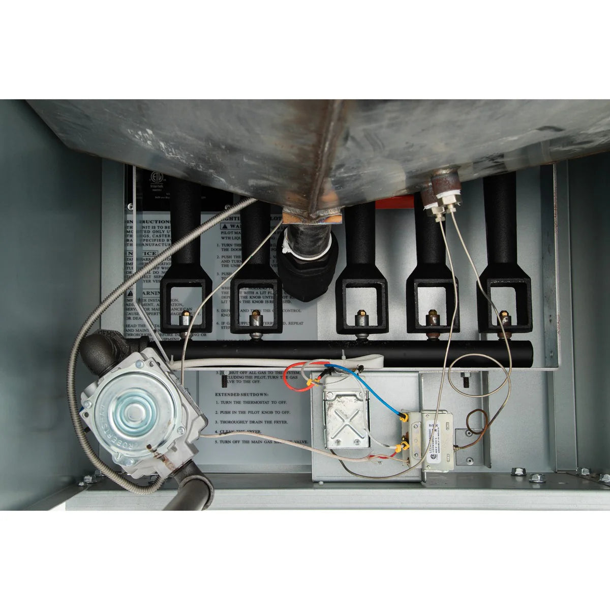 Interior view of a commercial fryer gas burner compartment, showing four black tubes, wiring, a silver gas valve, control board, and sensors. Labels with instructions are visible inside this 80lb oil capacity gas fryer unit.