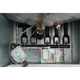 Close-up view of the inside of a commercial fryer, showing four black gas burners, ignition and sensor wires, metal pipes, a pressure switch, and an electrical control box with multi-colored wires in a metal compartment.