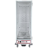 A full size, stainless steel heated holding cabinet with a clear front door. The interior offers perforated metal sides and one wire shelf, while the bottom includes red and black control knobs, switches, vents, and caster wheels.