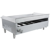 A large, rectangular commercial gas griddle with four sturdy legs, an open front panel revealing internal components, a control knob on the side, and a flat countertop griddle surface with raised edges and a rear splash guard.