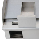 Close-up of an industrial, silver-colored metallic object resembling an Empura E-GRID-24 electric countertop griddle, with a rectangular slot and a raised, boxlike compartment above an open square section. The smooth surface suggests stainless steel construction.