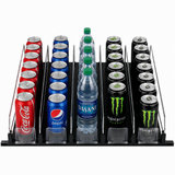 A black Empura Refrigeration shelf organizer holds five rows: left with Coca-Cola cans, second with Pepsi, third with Dasani water bottles, and right with Monster Energy. Each row features product pusher dividers and clear front stoppers for neat display.