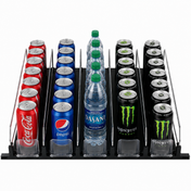 A black Empura Refrigeration shelf organizer holds five rows: left with Coca-Cola cans, second with Pepsi, third with Dasani water bottles, and right with Monster Energy. Each row features product pusher dividers and clear front stoppers for neat display.