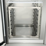 The image shows the inside of an Empura E-PR6 commercial stainless steel refrigerator with empty metal racks on both sides and a single 6-pan rack shelf at the top. The clean, reflective surfaces stand out as the door is slightly open.