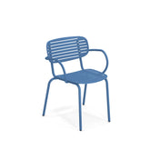 A modern blue solid steel chair with a slatted seat and backrest. Named the Mom Stacking Armchair, it features rounded armrests and four simple legs, giving this outdoor chair a sleek, minimalist design on a white background.