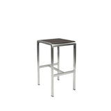 The Sid Barstool features a brushed metal frame and a rectangular, dark wood-look aluminum seat. Perfect for outdoor/indoor spaces, its minimalist and industrial design includes four straight legs and a sturdy horizontal support bar.