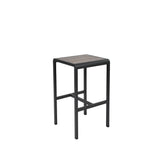 The Sid Barstool features a modern, square design with a black metal frame and a slatted, wood-look aluminum seat. Suitable for outdoor/indoor use, it offers stability with four straight legs and two horizontal support bars on each side.
