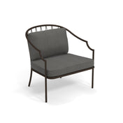 The Como Lounge Arm Chair features a modern design with a dark steel wire frame. Suitable for indoor/outdoor spaces, it has a curved backrest with vertical bar details and plush, textured gray cushions for added comfort.