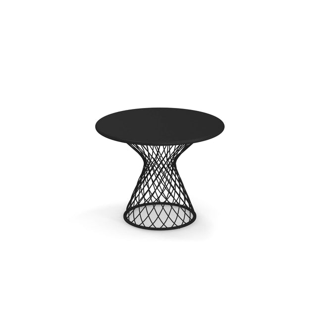 A round black Como Side Table with a solid top features an open, hourglass-shaped base crafted from steel wire in a striking diamond pattern, making it perfect for both indoor and outdoor settings. The table is centered on a plain white background.