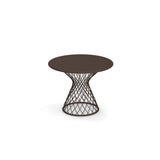 A round, dark brown Como Side Table with a solid top and an open, steel wire lattice-style base that narrows toward the middle and widens at the bottom, giving it a modern, sculptural look. Perfect for indoor/outdoor spaces, it sits alone on a white background.