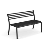 The Segno Stacking Bench is a sleek black steel bench with a slatted backrest and seat, four straight legs, and slightly curved back legs. This modern outdoor bench offers both support and style, set against a clean white background.