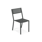 A modern, dark gray Segno Stacking Side Chair crafted from e-coated steel with four straight legs, a slightly curved backrest, and a seat featuring horizontal slats. This outdoor stacking chair is photographed on a white background, facing slightly right.