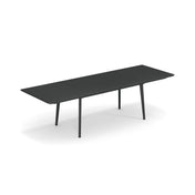 A long, modern Plus4 Extension Table with a matte black finish, slim solid steel top, and four angled legs. The extendable section in the middle allows for extra seating. The background is plain white.
