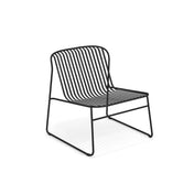 A modern black metal chair with a minimalist design, inspired by the Riviera Stacking Lounge Chair. Crafted from wrought iron, it’s perfect for outdoor/indoor use, featuring curved parallel rods and sled-style legs that cast striped shadows.