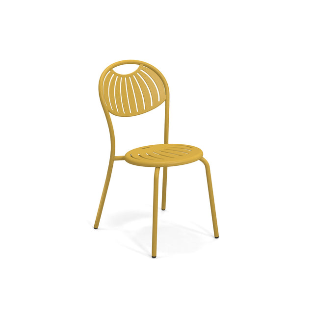 A modern yellow stacking side chair with a round, curved backrest and seat, both featuring slotted, leaf-like cut-out patterns. The chair has four slender legs and is set against a plain white background.