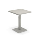 A modern square Lock Table with a light gray, flat tabletop. Crafted from e-coated steel, it features a central rectangular pedestal with a circular accent, and a flat square base. The minimalist design suits both outdoor/indoor spaces. Background is plain white.