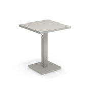 A modern square Lock Table with a light gray, flat tabletop. Crafted from e-coated steel, it features a central rectangular pedestal with a circular accent, and a flat square base. The minimalist design suits both outdoor/indoor spaces. Background is plain white.