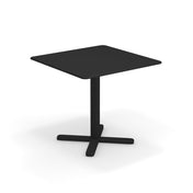 A modern, square black Darwin Tilt Top Table with a flat top and a single central pedestal base that splits into four feet at the bottom, forming an X-shape. This solid steel dining table is set against a plain white background.