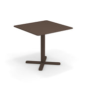 A simple brown Darwin Tilt Top Table with a single central pedestal base and four feet extending outward in a cross shape, set against a white background.
